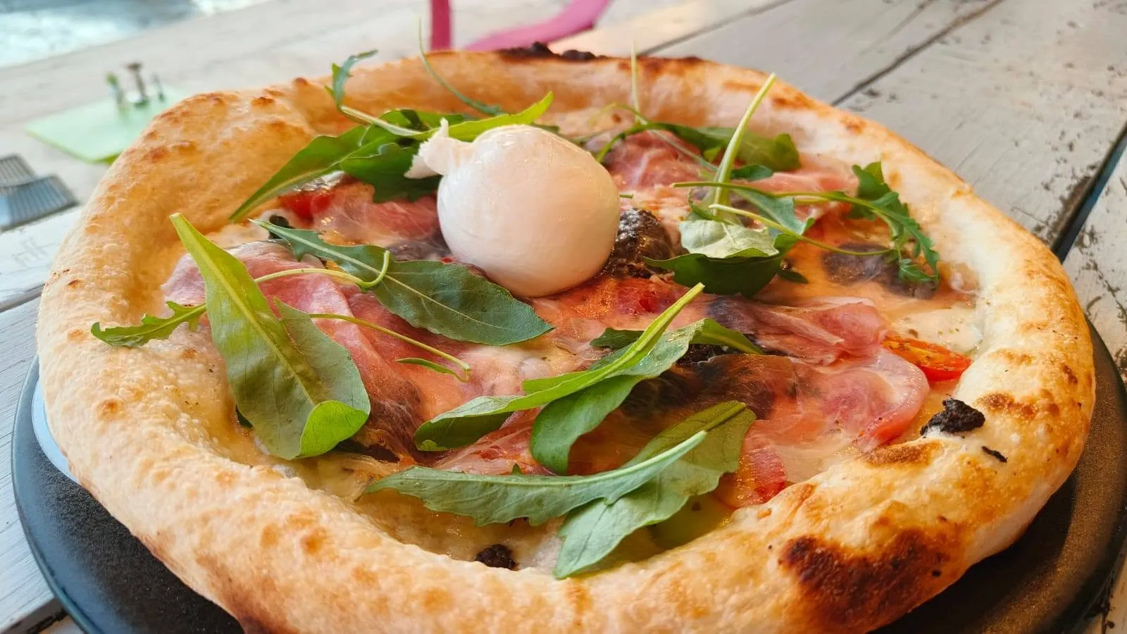 Pizza topped with burrata, prosciutto and rocket