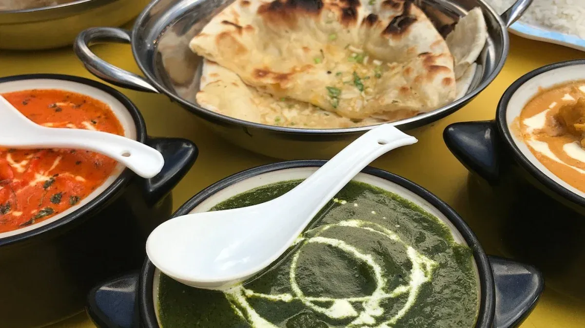 Palak curry with naan and additional Indian curries